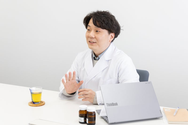 【画像】着席し、説明をしている様子の白衣姿の男性