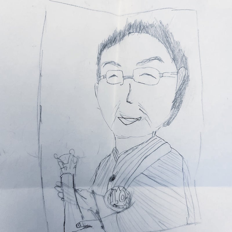 【写真】トロフィーを持っている梅沢さんの似顔絵