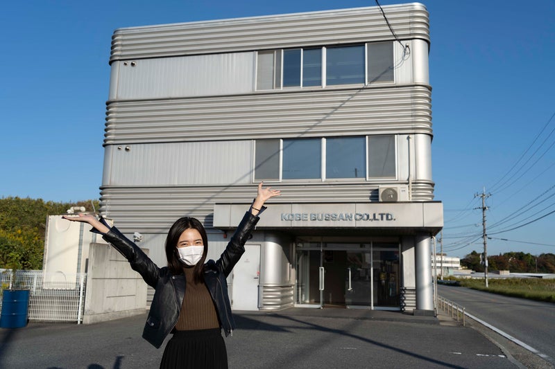 神戸物産本社の前で編集Mが笑顔で手を上げている写真