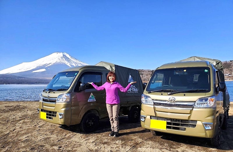 富士山を背景に2台のキャンピングカーの前に立つ松本さんの写真