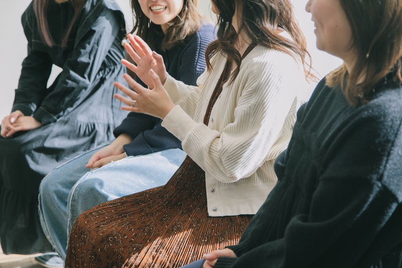 【写真】4人の女性が椅子に座って談笑している