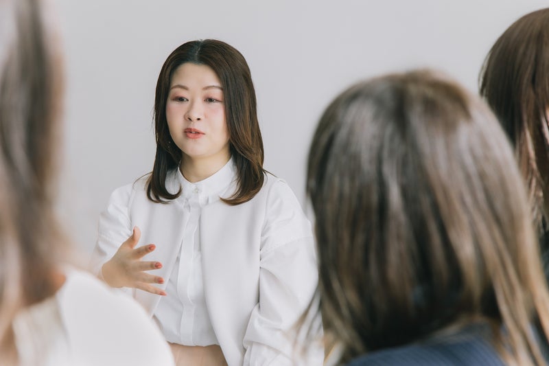 【写真】話している白い服の女性とそれを聞いている女性たち