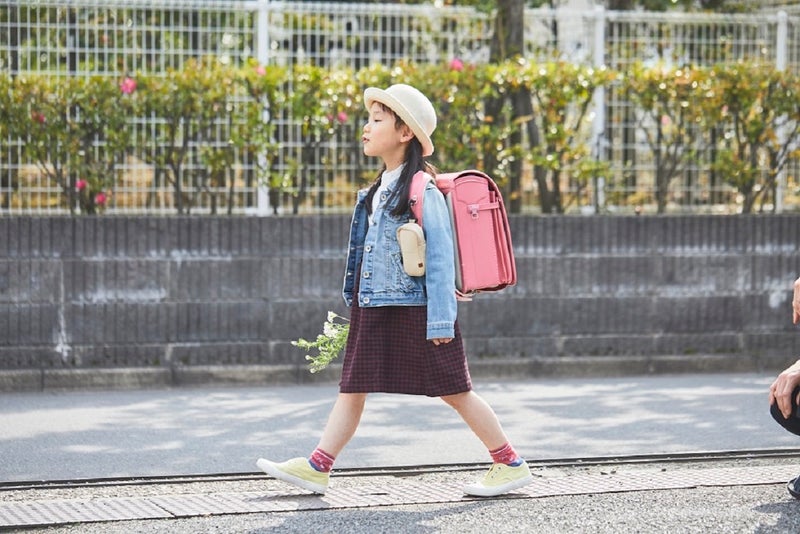 ランドセルを背負って通学する女の子の写真