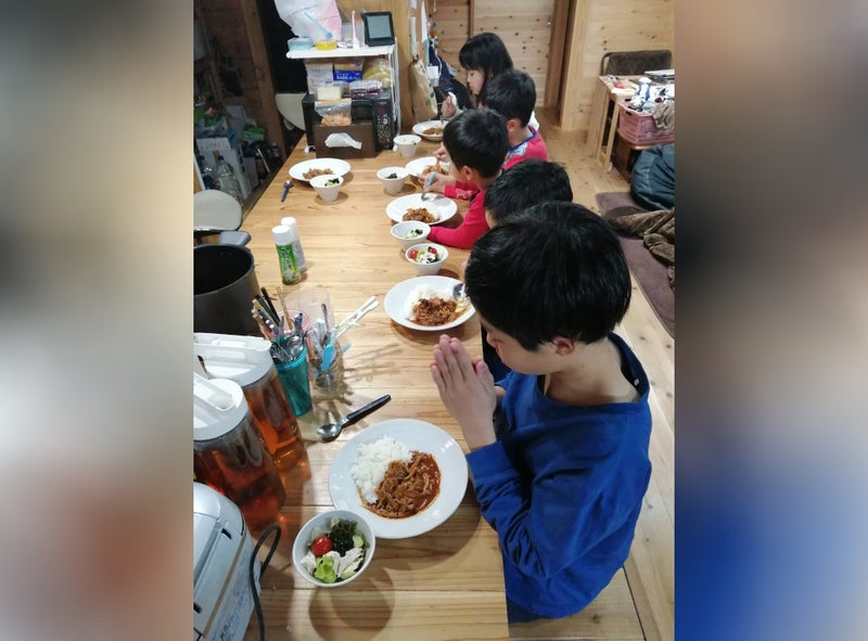 一列に並んで夕食を食べる5人の子どもの写真