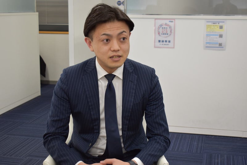 紺色のスーツを着た男性が話している写真