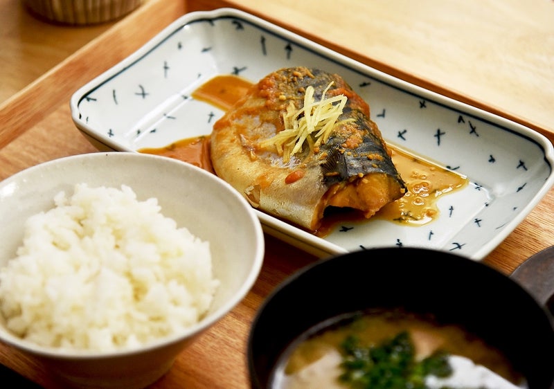 木製のトレイに並んでいるさばの味噌煮とご飯と味噌汁の写真