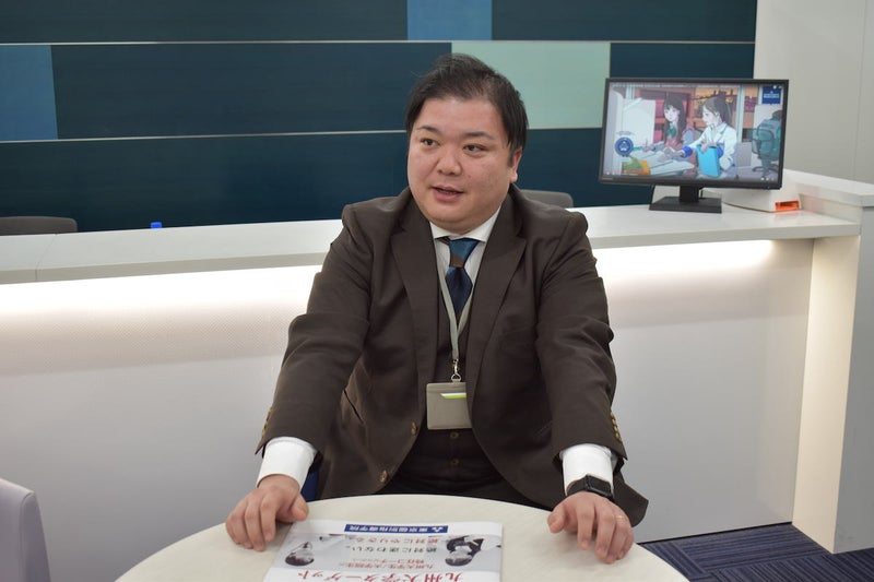 茶色いスーツを着た男性が話をしている写真