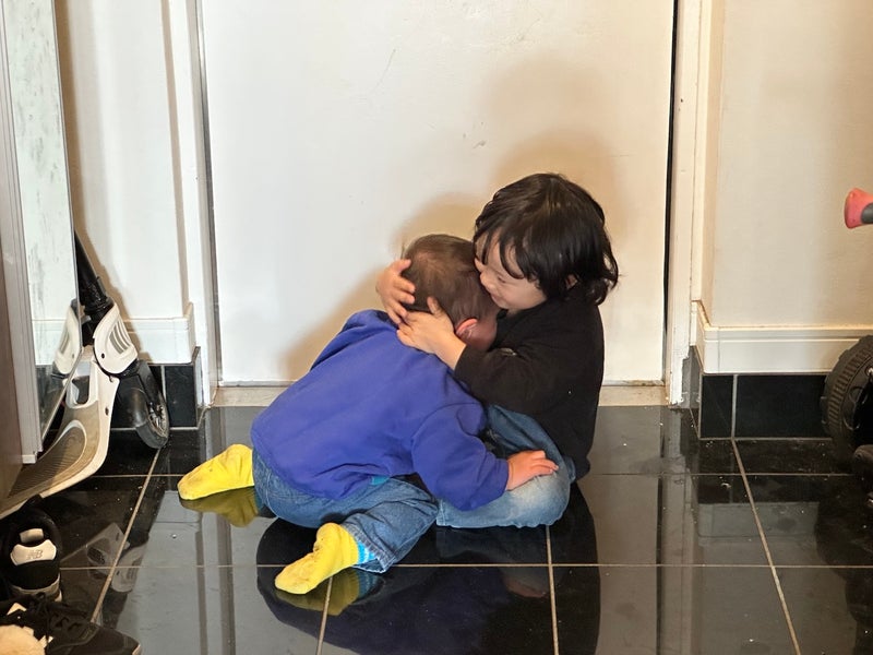 【写真】2人の小さな男児が玄関でじゃれ合っている