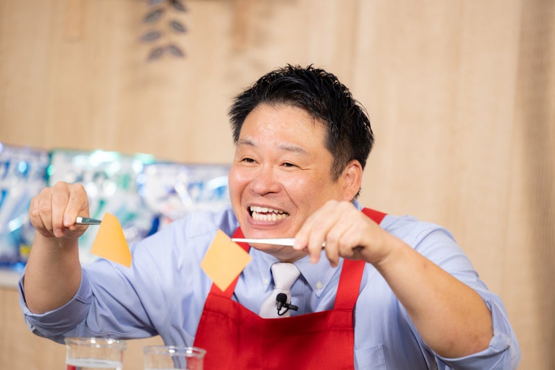 【画像】ピンセットで皮脂汚れを再現した検証素材を両手にもつレジェンド松下さん