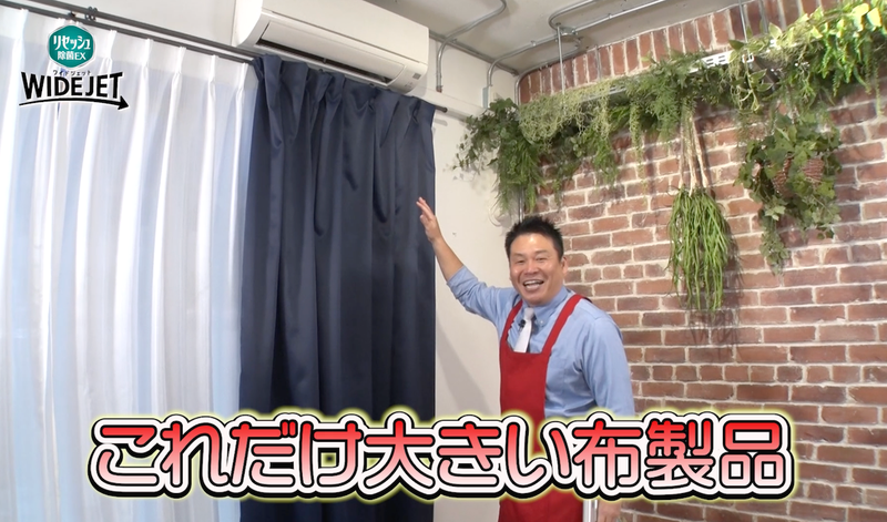 紺色のカーテンの前に立つレジェンド松下さんの写真